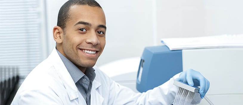 A clinical researcher in the lab smiling. Take the Clinical Research Program at Oxford.
